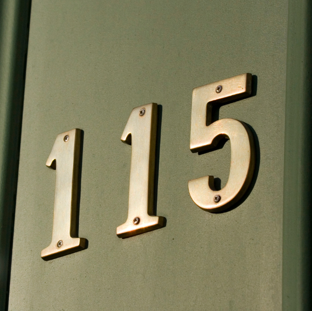 Gold house number 115 on a green door