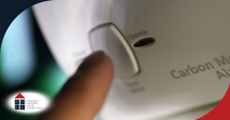 A person pressing the button on a carbon monoxide alarm.