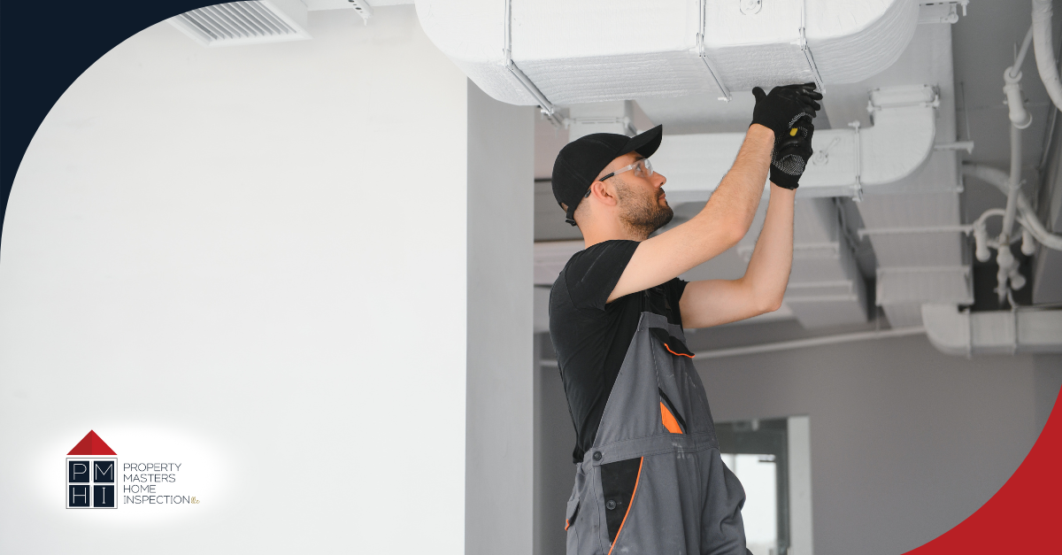 A worker inspecting ductwork in a ceiling.