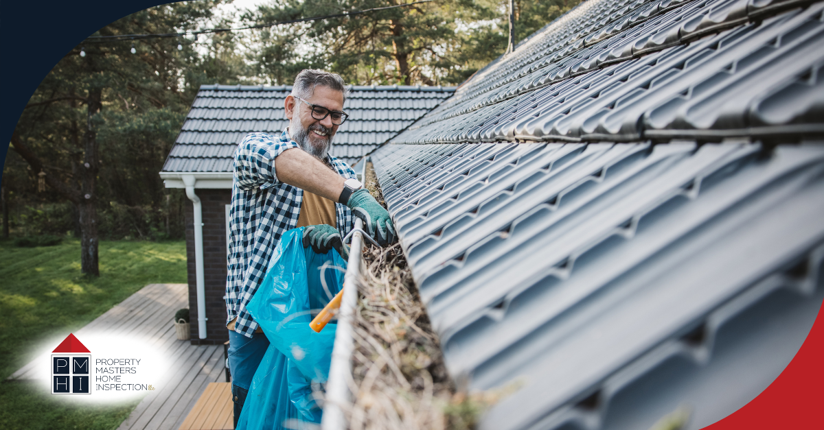 A person cleaning debris from the gutters on a roof.
