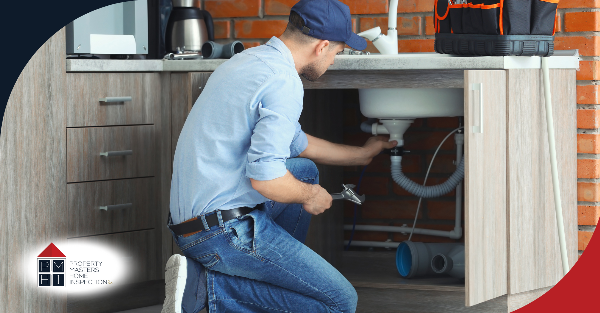 Inspector checking plumbing under kitchen sink.